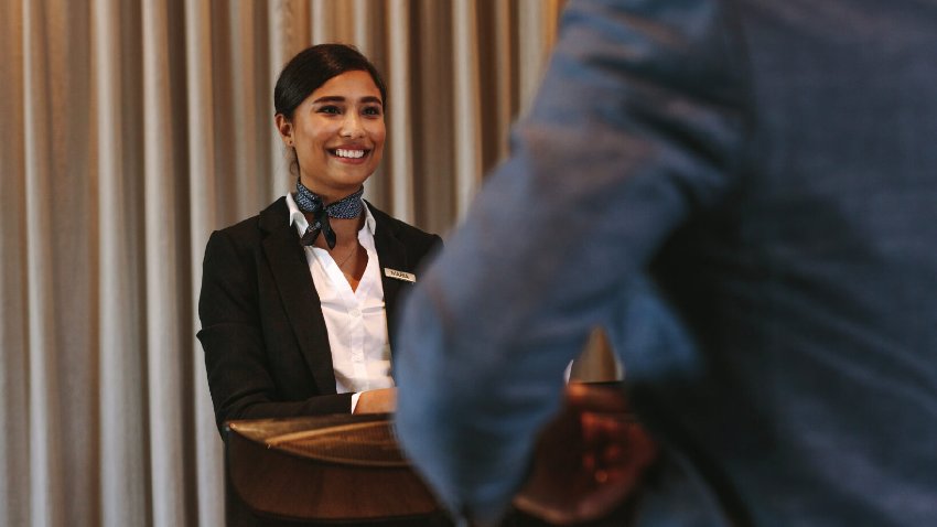 Portrait of female concierge standing at reception to welcome guest