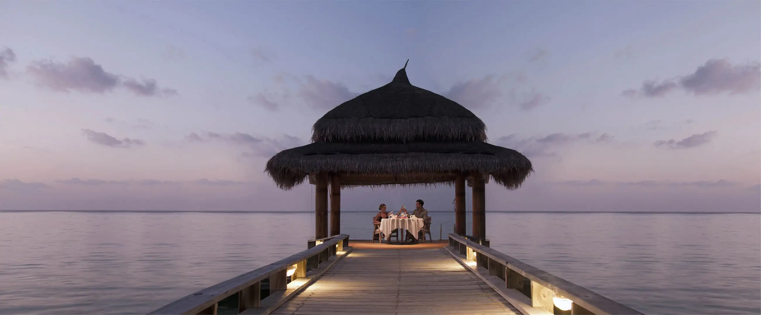 A couple enjoying candle light dinner on tropical dock