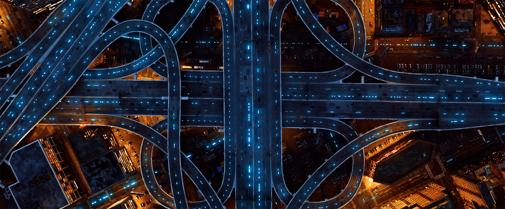 Looking down during the nighttime over a large traffic interchange with several ramps and loops