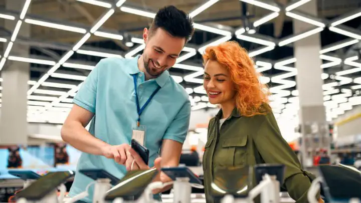 A salesman displaying a mobile device to a customer at electronic store