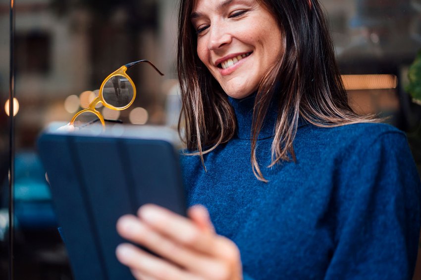 A woman smiling holding a tablet in hand