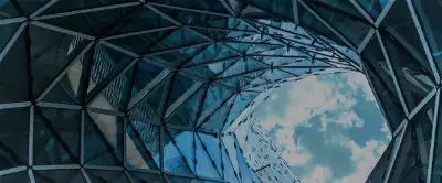 A look up at the cloudy sky surrounded by the glass windows of tall building 