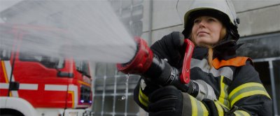 Female firefighter shooting water out of a firehose