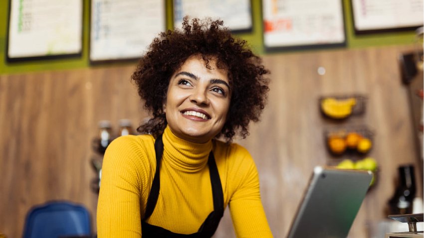 A woman with a smile working on a laptop