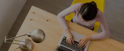 Woman sitting at a table typing on a laptop