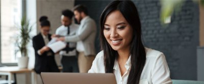 A woman smiling while working on a laptop at the office