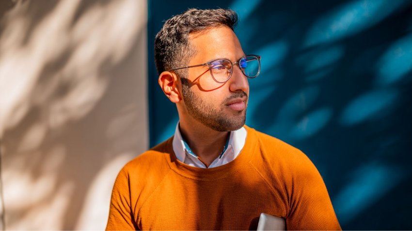 Headshot of a man in orange t-shirt looking sideways