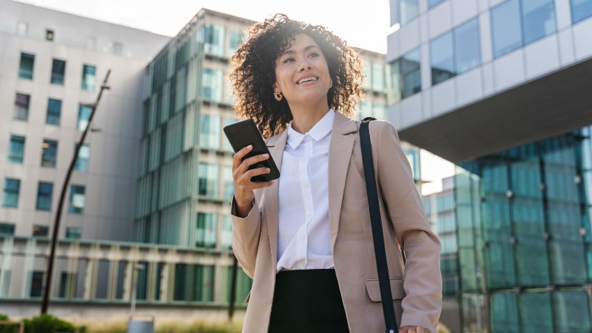 A well suited young happy woman in a corridor of business park with a mobile