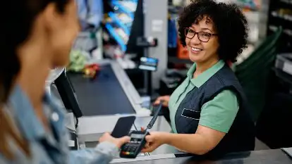 A cashier accepting payment with a card machine from a customer