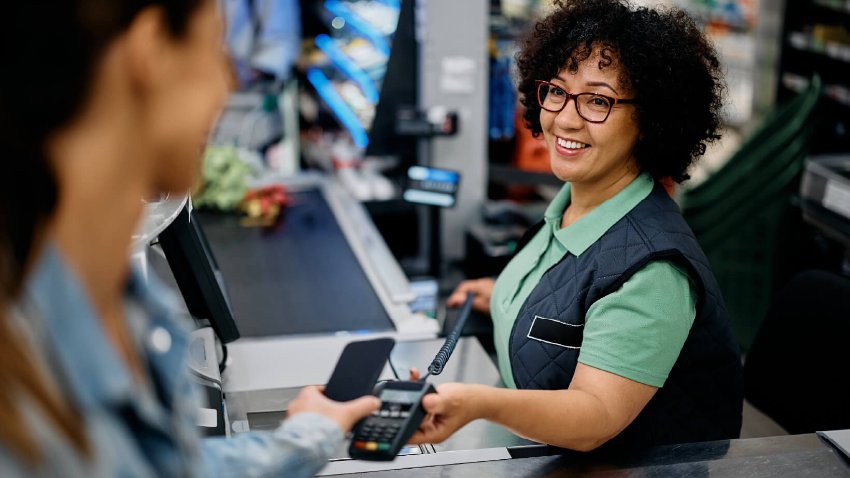 A cashier accepting payment with a card machine from a customer