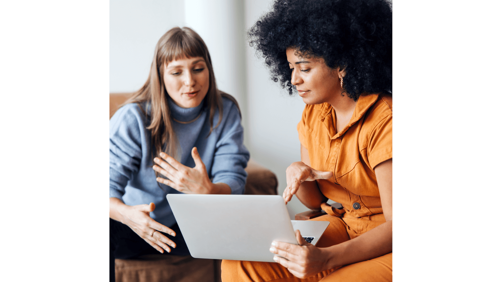 Two young woman in a business meeting looking at laptop screen