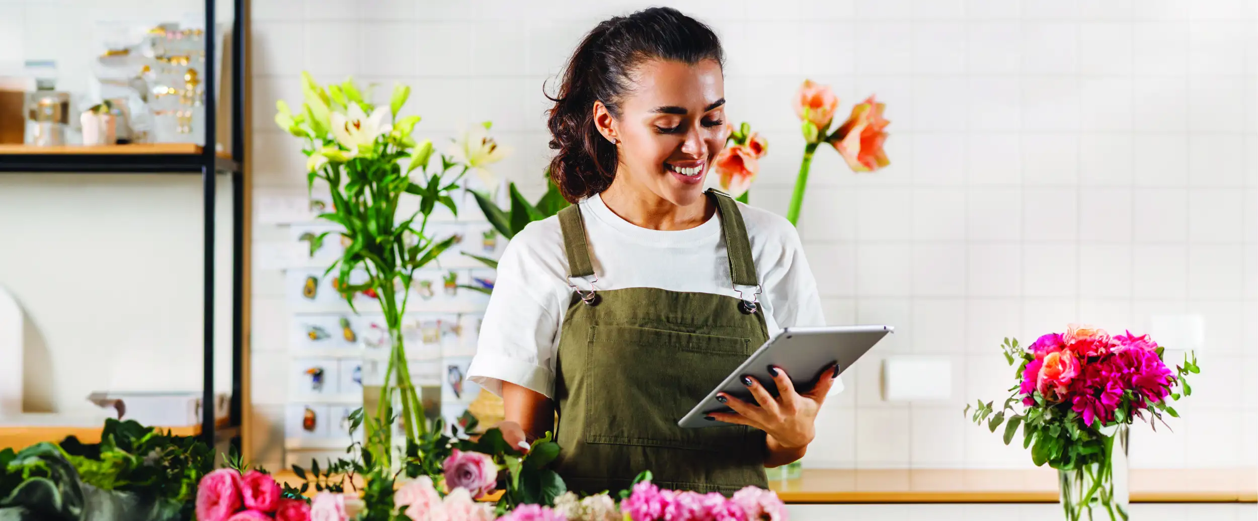 Woman arranging flowers while looking at a tablet