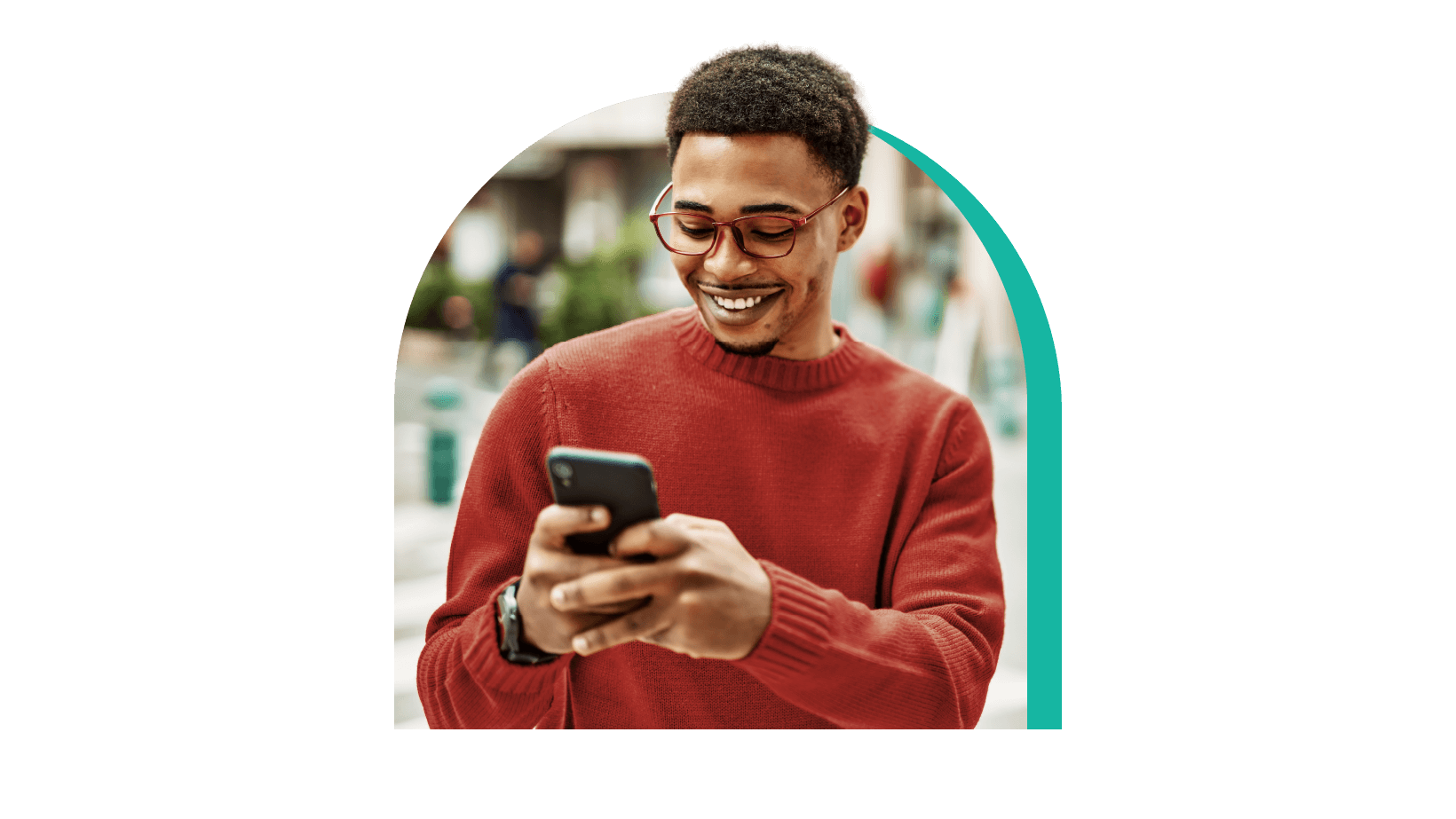 A young man in a orange t-shirt looking at phone screen with a smile