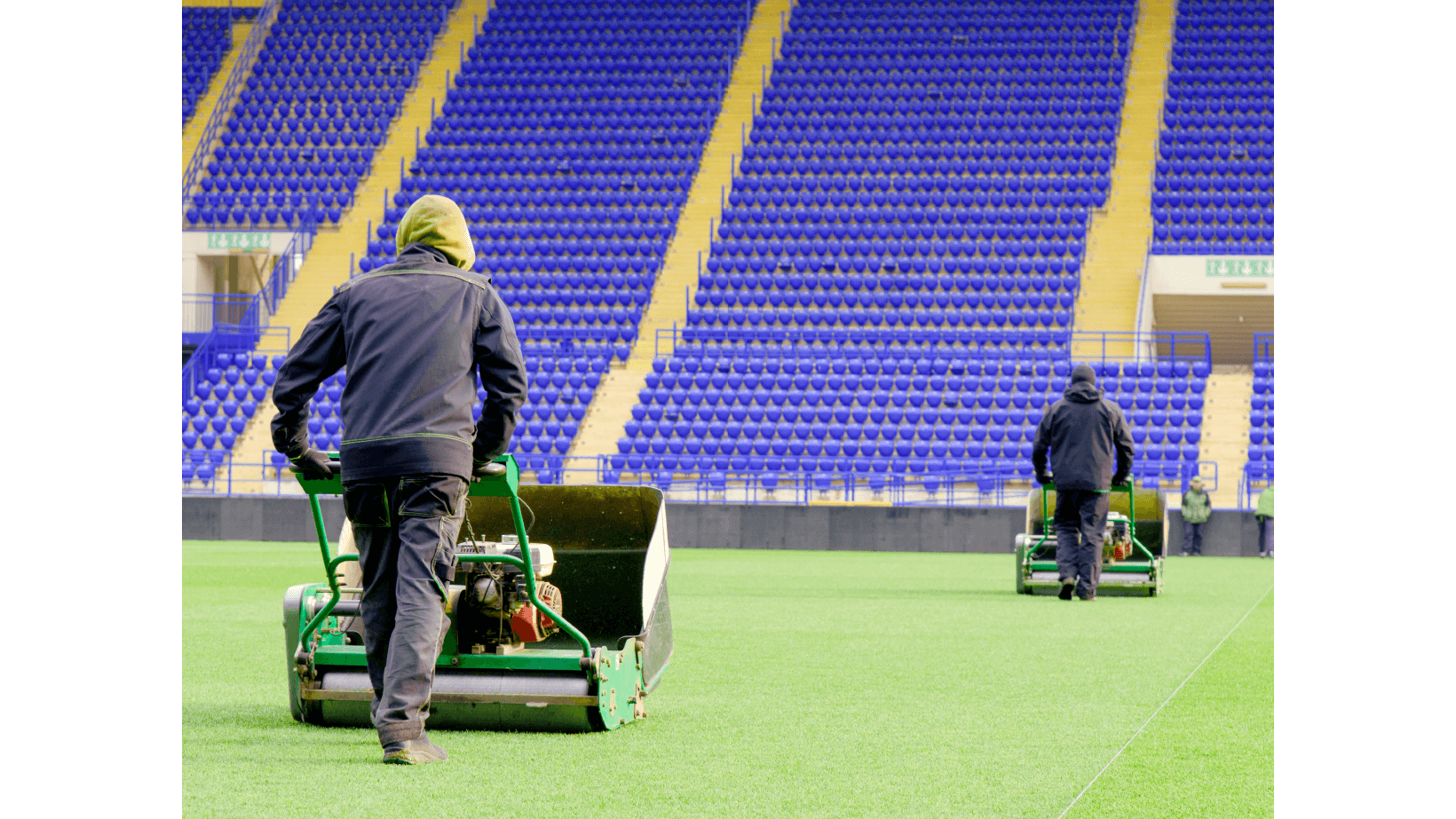 Landscape maintenance crew cutting grass in football field