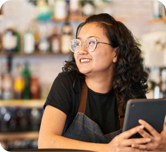 A woman with a smiling face holding tablet in her hand and sitting at the cafe