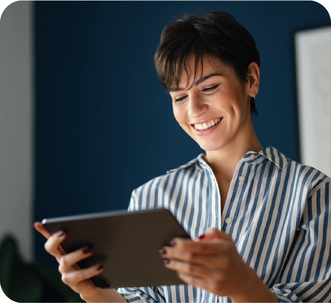 A woman smiling while looking at tablet screen