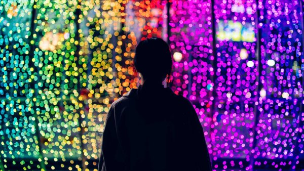 person silhoutted against multicolored lights