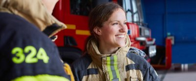 Female firefighter smiling while standing in front of a fire truck