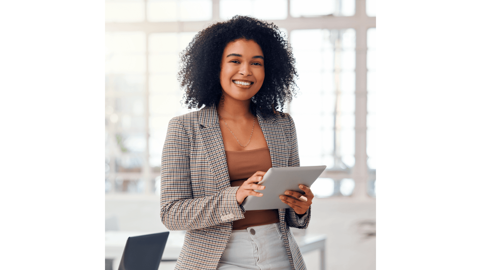 A smiling woman in a corporate uniform holding a tablet