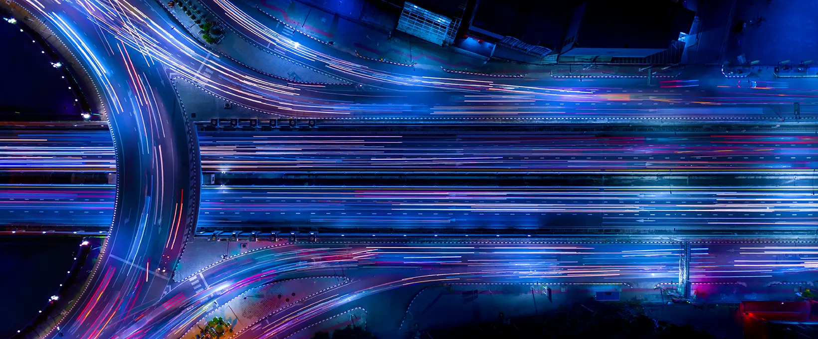 Time lapse aerial photo of traffic on freeway interchange in blues and purples
