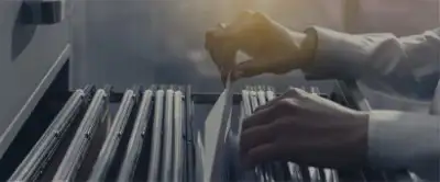 Person browsing through the folders in a filing cabinet