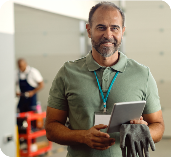 An employee in green t-shirt with a tablet and glove in hand