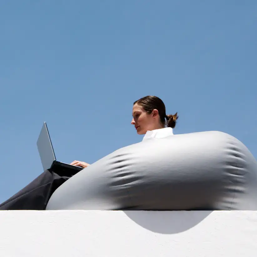 A woman working on a laptop while sitting on a large bean bag chair