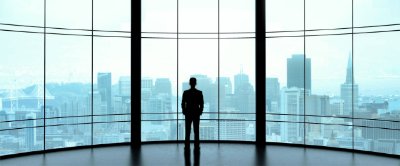 Man admiring the cityscape out the window of a tall building 