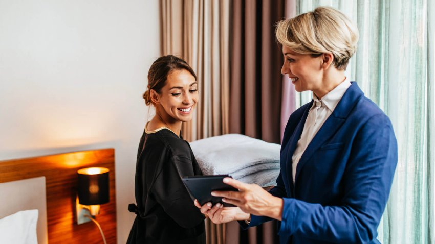 Housekeeping Supervisor checking on one of her Room Attendants as she makes the bed in the hotel room